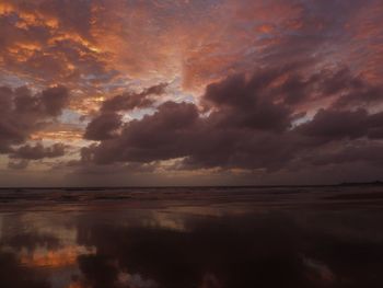 Scenic view of sea against dramatic sky during sunset