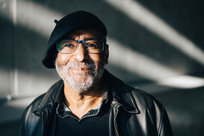 Portrait of smiling senior man against wall