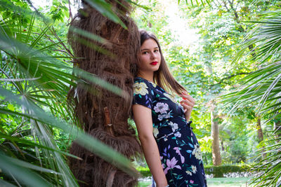 Portrait of young woman against tree