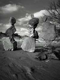 Stacked stones on field against sky