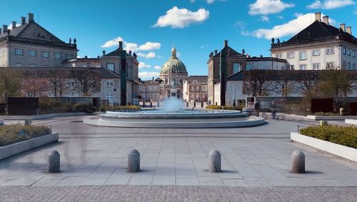 Fountain in front of historic building against sky amalienborg denmark 