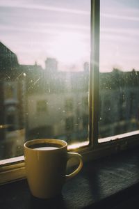 Coffee cup on table by window during rainy season