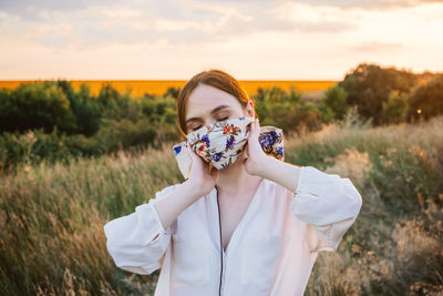 Portrait of woman standing on field against sky during sunset