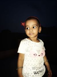 Portrait of cute girl standing against black background