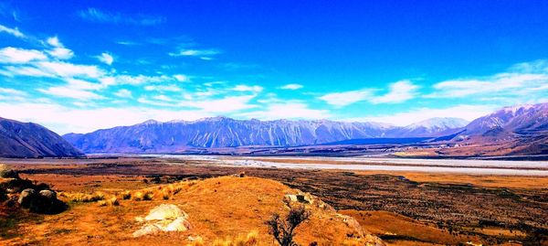 Scenic view of landscape and mountains against blue sky