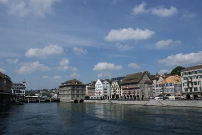 City at waterfront against cloudy sky