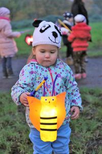 Cute girl with illuminated toy standing on field