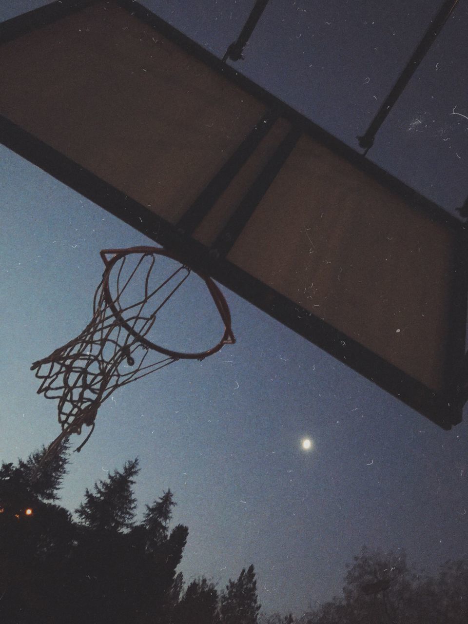 LOW ANGLE VIEW OF BASKETBALL HOOP AGAINST SKY AT DUSK