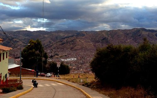 Road leading towards mountains against cloudy sky