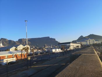 Street by buildings against clear blue sky