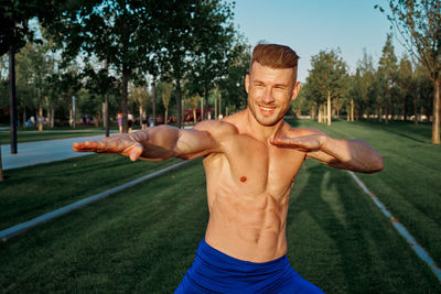 Portrait of young man exercising on field