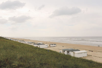 High angle view of huts at beach seen from grassy cliff