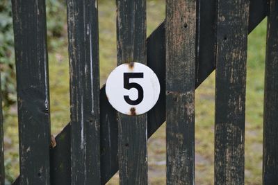 Close-up of sign on wooden fence