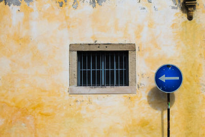 Close-up of road sign and window on yellow building