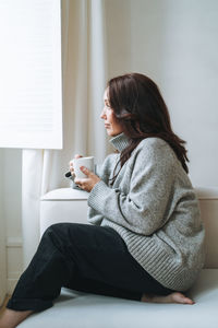 Young woman sitting on sofa at home