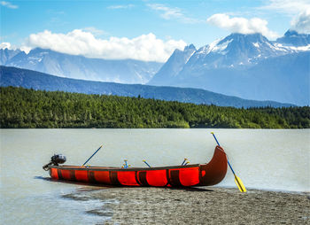 Scenic view of lake with a canoe against mountains, alaska