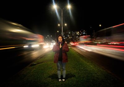 Woman standing with eyes closed and hands clasped on city street at night