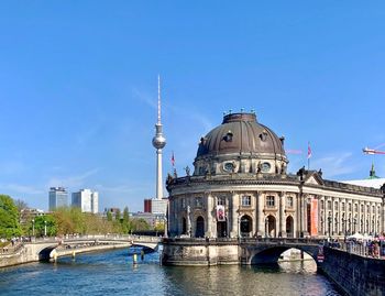 View of canal and buildings against clear blue sky