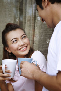 Couple talking while having coffee against wall