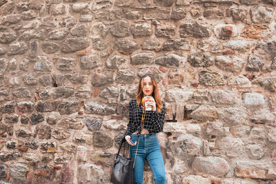 Portrait of a woman standing against wall