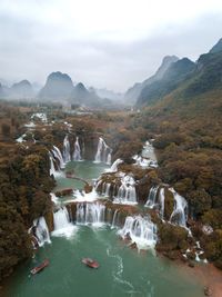 Aerial view of waterfall against mountains