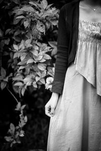 Midsection of woman standing against plants