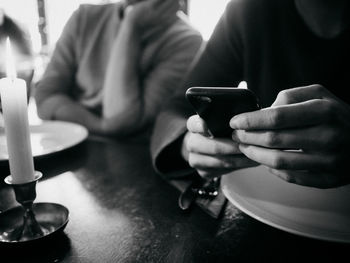 Close-up of man using smart phone while sitting with friend at table