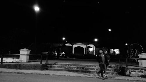 Man and woman in illuminated city against sky at night