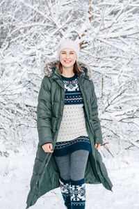 Woman in green jacket winter clothes, ethnic pattern woolen dress and hat walking in park forest