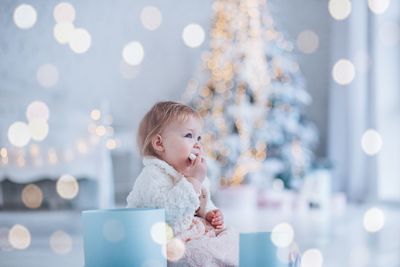 Little girl sorting new year gifts under the christmas tree