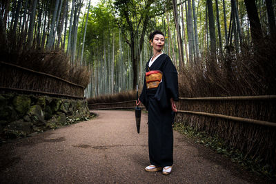 Full length portrait of young man standing in forest