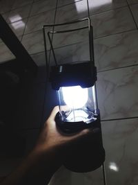 Close-up of hand holding illuminated electric lamp