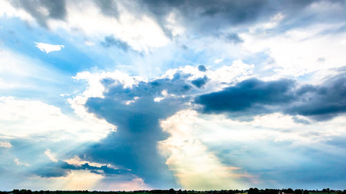 Low angle view of sunlight streaming through clouds