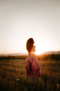 Woman on field against clear sky during sunset