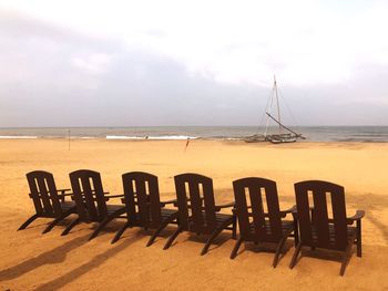 Chairs on beach by sea against sky