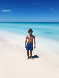 Full length of boy running at beach against sky