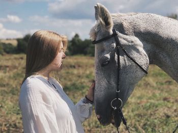 Side view of woman standing by horse outdoors