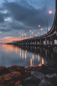 Illuminated bridge over river against sky