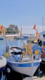 Boats moored at harbor against clear blue sky