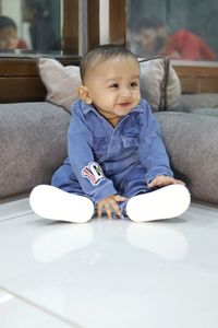 Cute boy sitting on sofa at home