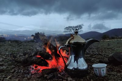 Coffee pot next to the fire in a dark cloudy weather