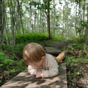 Boy lying on wood in forest