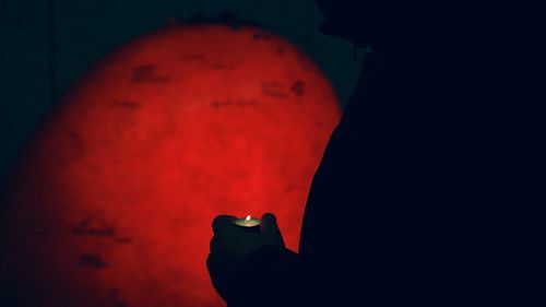 Close-up of hand holding illuminated red light