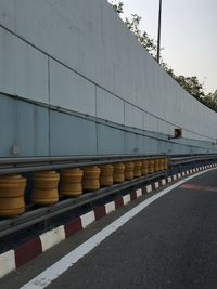 Road by wall against sky in city