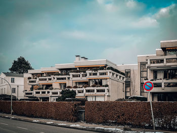 Road by buildings against sky