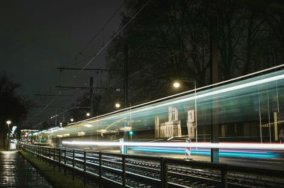 Light trails on bridge in city against sky at night