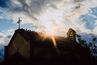 Low angle view of cross on building against sky
