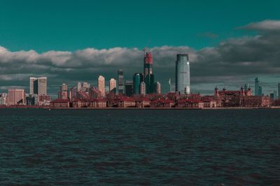 Sea by buildings against sky in city