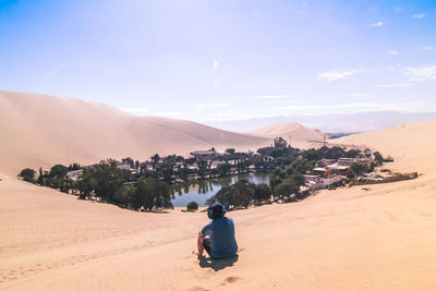 Rear view of man on desert against sky