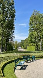 Empty bench in park against sky